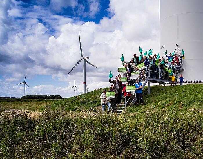 Gruppe von Menschen vor einem Windrad